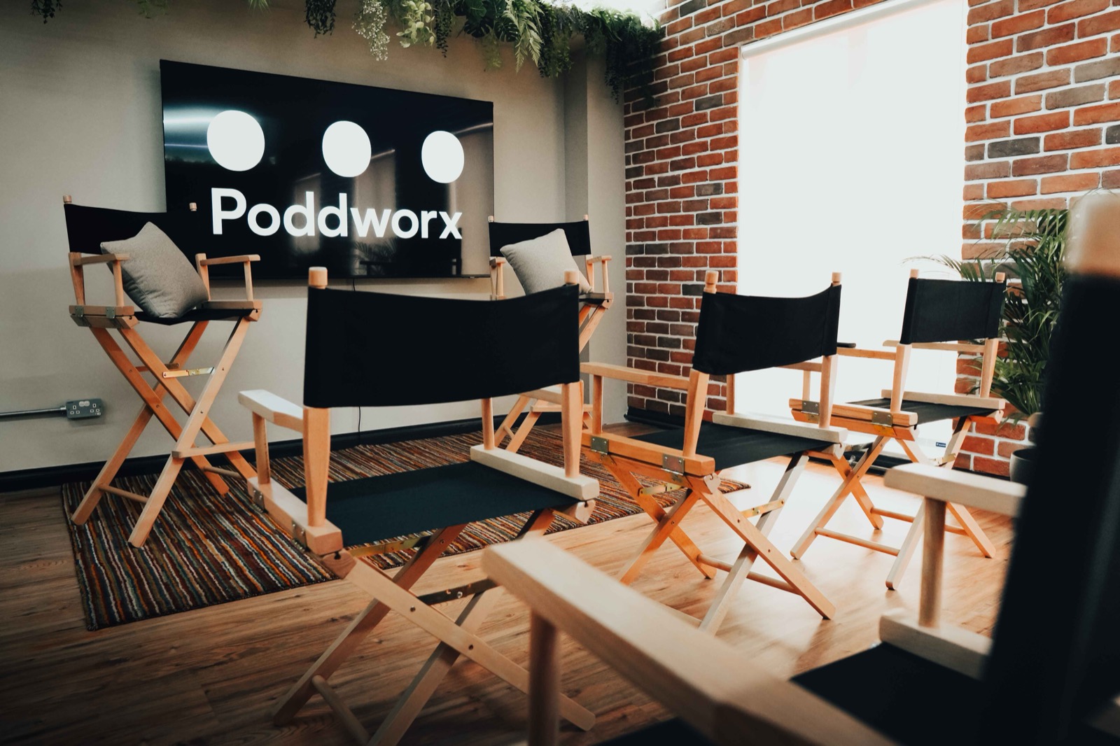 Poddworx studio room with director chairs and the Poddworx logo on screen, ready for a podcast planning session