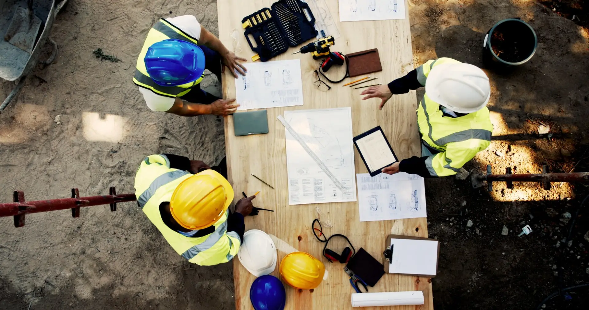 group of builders and project managers around a table with plans and tools, birds eye view 