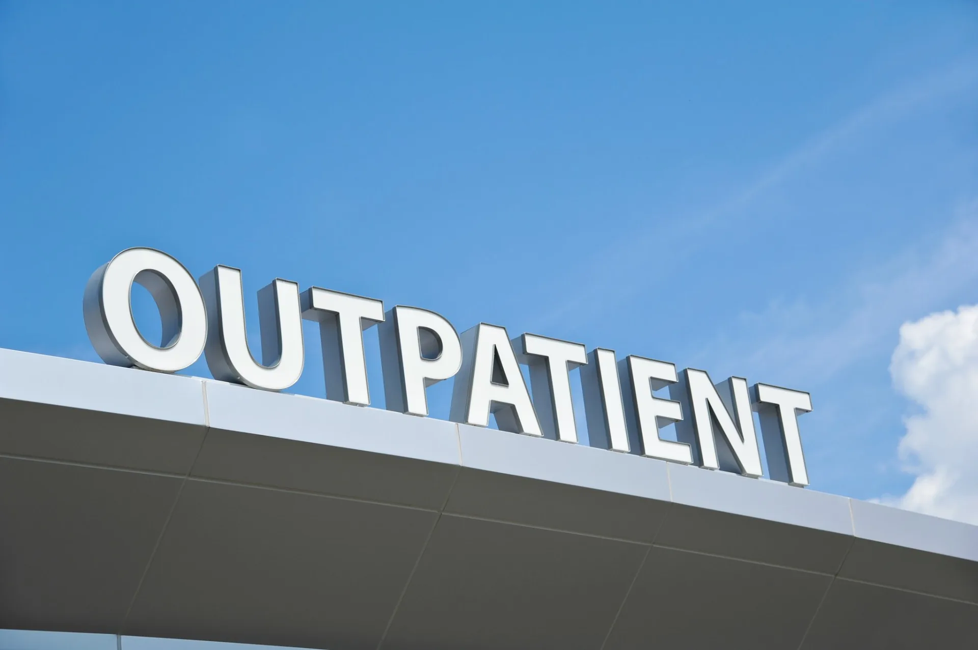 Outpatient sign on top of a building with blue sky behind