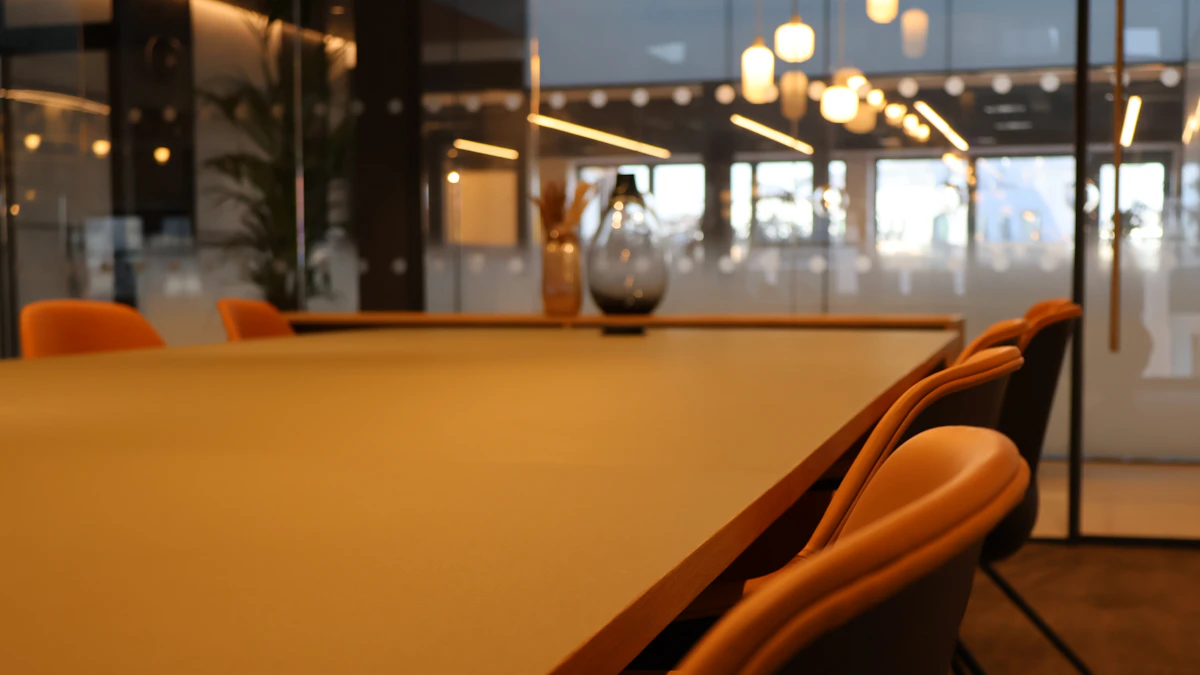 An empty conference table bathed in morning sunlight with chairs neatly arranged, representing an organized and calm operational environment