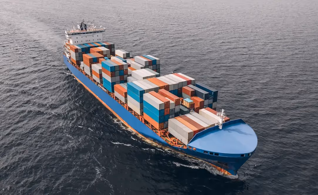 Large blue cargo ship carrying numerous colorful shipping containers sailing on the ocean.