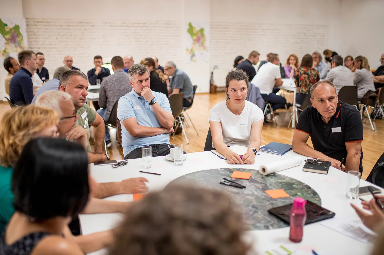 Skupina ľudí diskutujúcich pri stole v konferenčnej miestnosti počas workshopu.