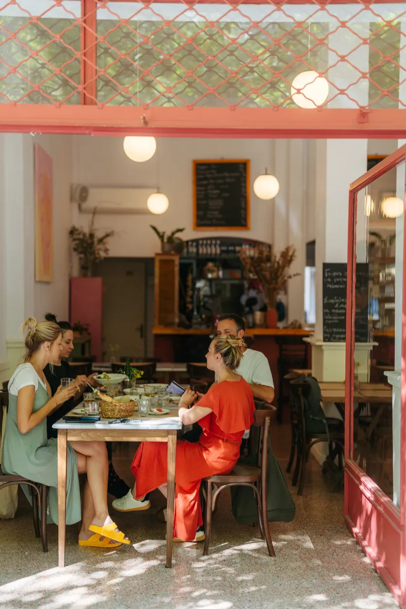 A group of people sitting together and talking at a table inside a brightly lit restaurant.