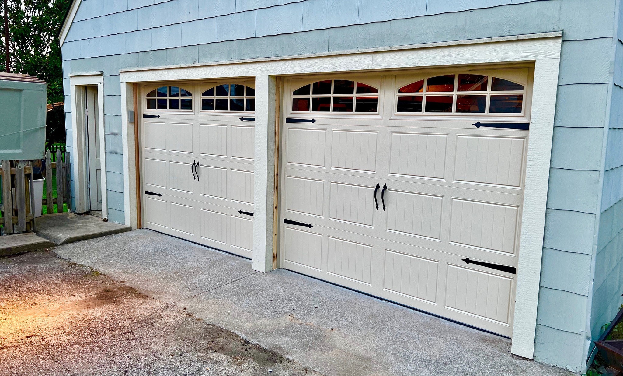 2 Doorlink 3630 steel garage doors in Almond with long panel glass in the top section. Decorative hardware attached.