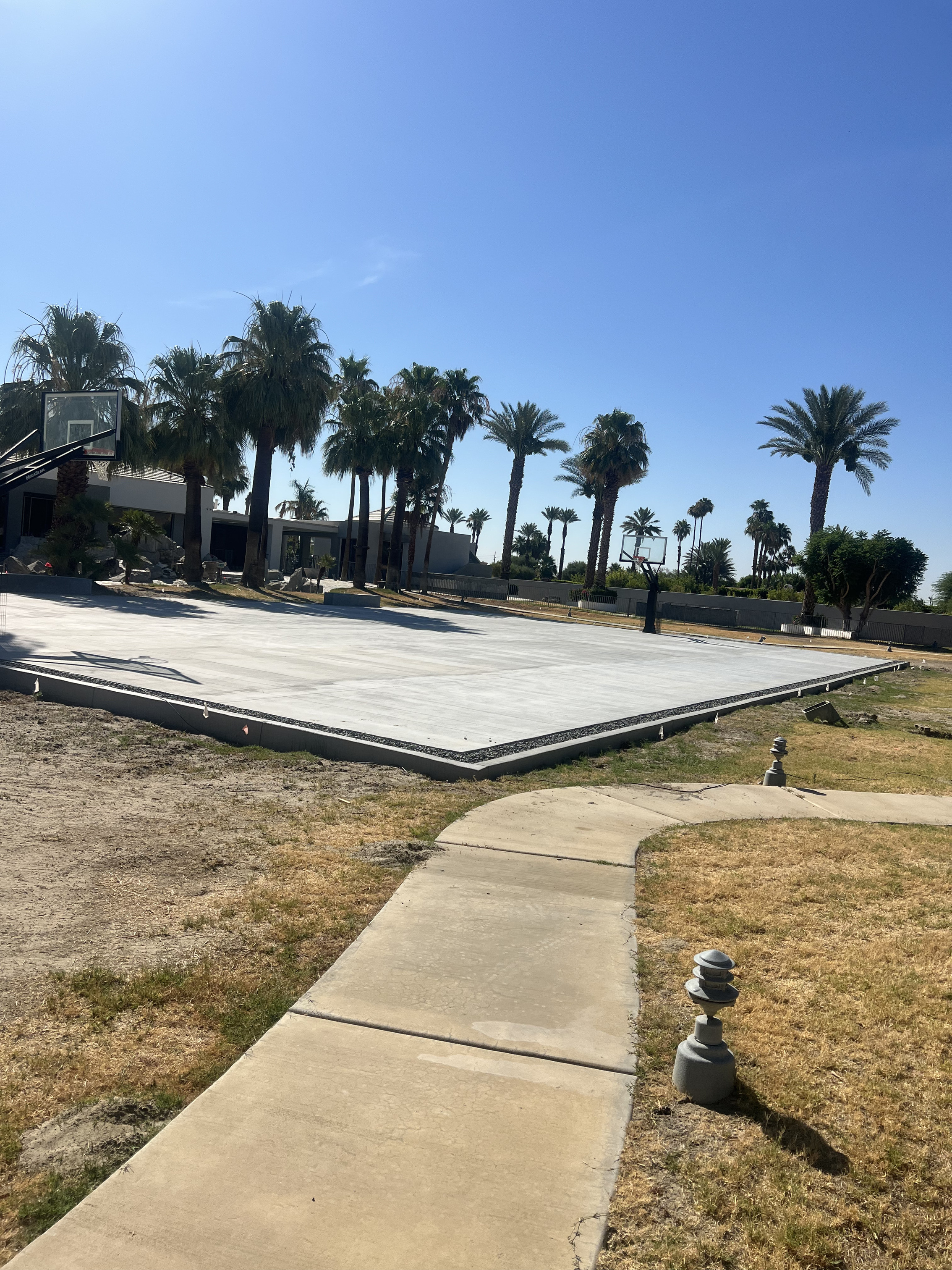 Concrete basketball court with hoops and saw-cut lines in La Quinta, CA