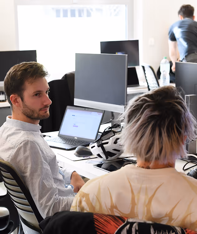 Deux personnes discutant sérieusement devant des ordinateurs
