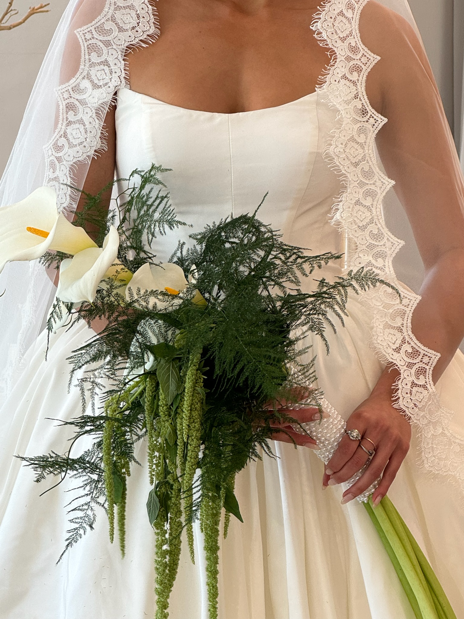 A bride wearing a satin bridal gown and holding a flower bouquet