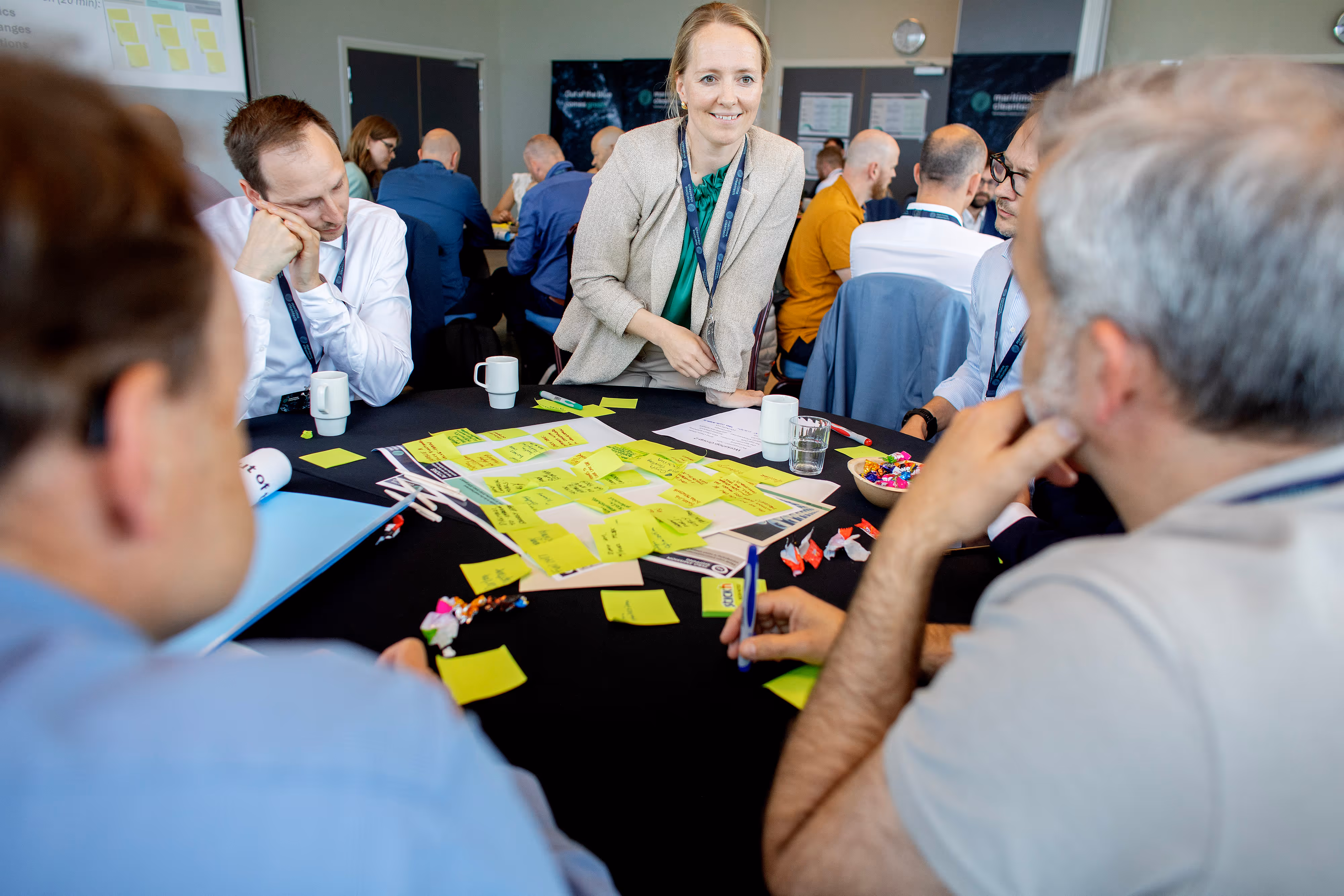 People sitting around a table covered in sticky notes during a workshop discussion.