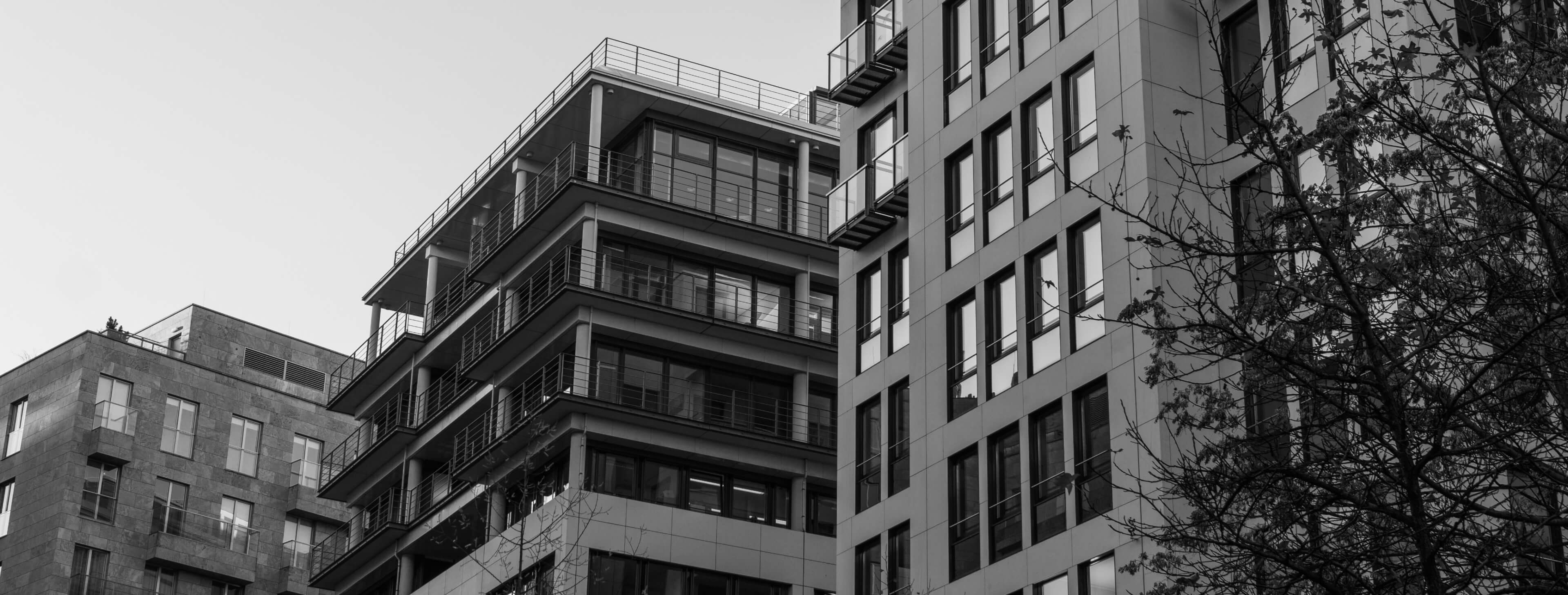 Image of modern urban buildings with large windows, balconies, and minimalist design.