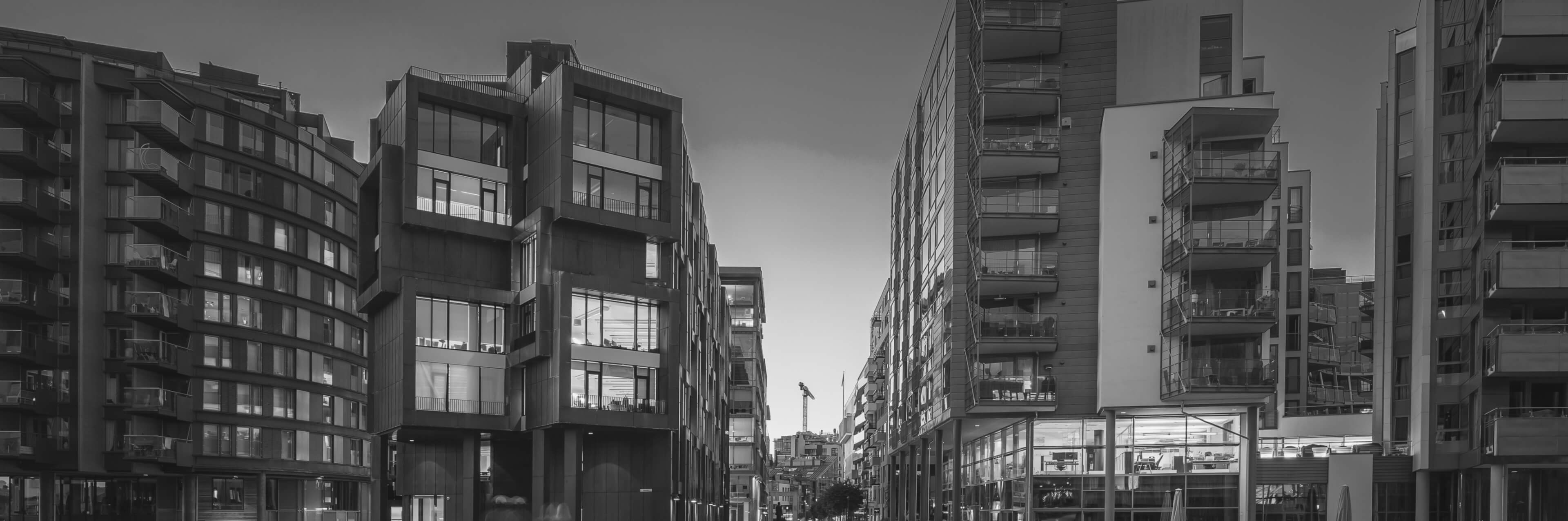 Photo of a modern urban street flanked by tall buildings with large windows.