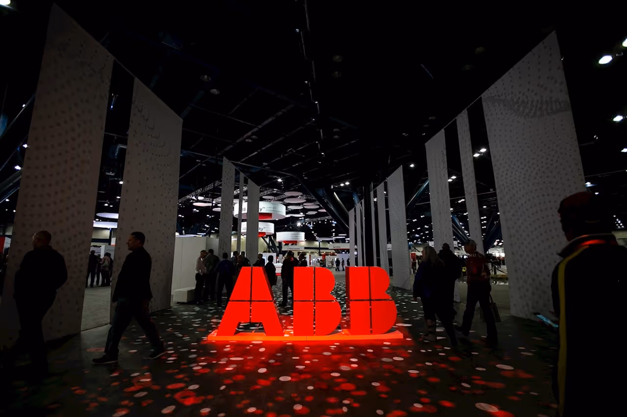 Illuminated red ABB logo in a dimly lit indoor event space with people walking around.