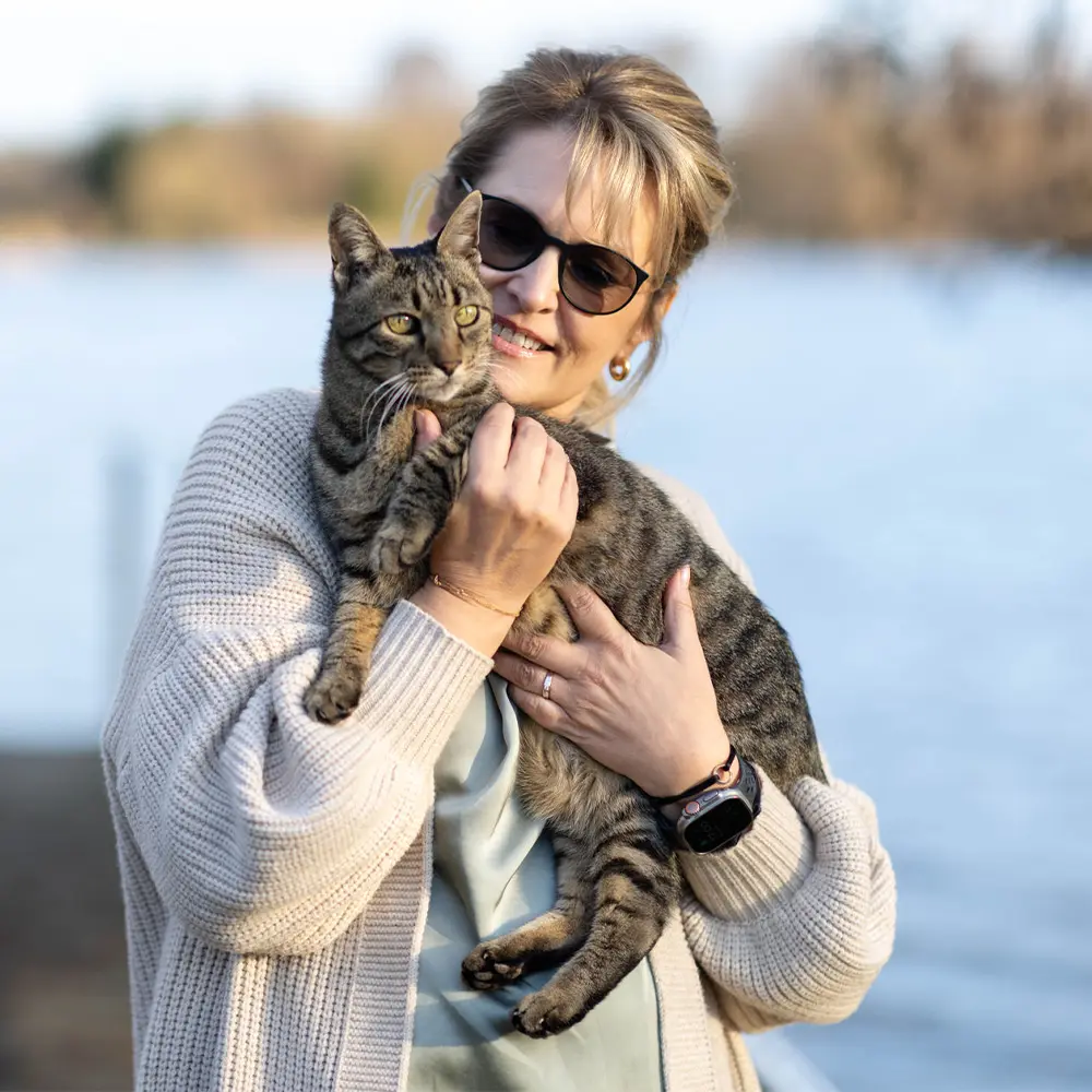 Nicole Flockenhaus sitzt privat mit ihrem Kater Pepper in der Natur und kuschelt mit ihm
