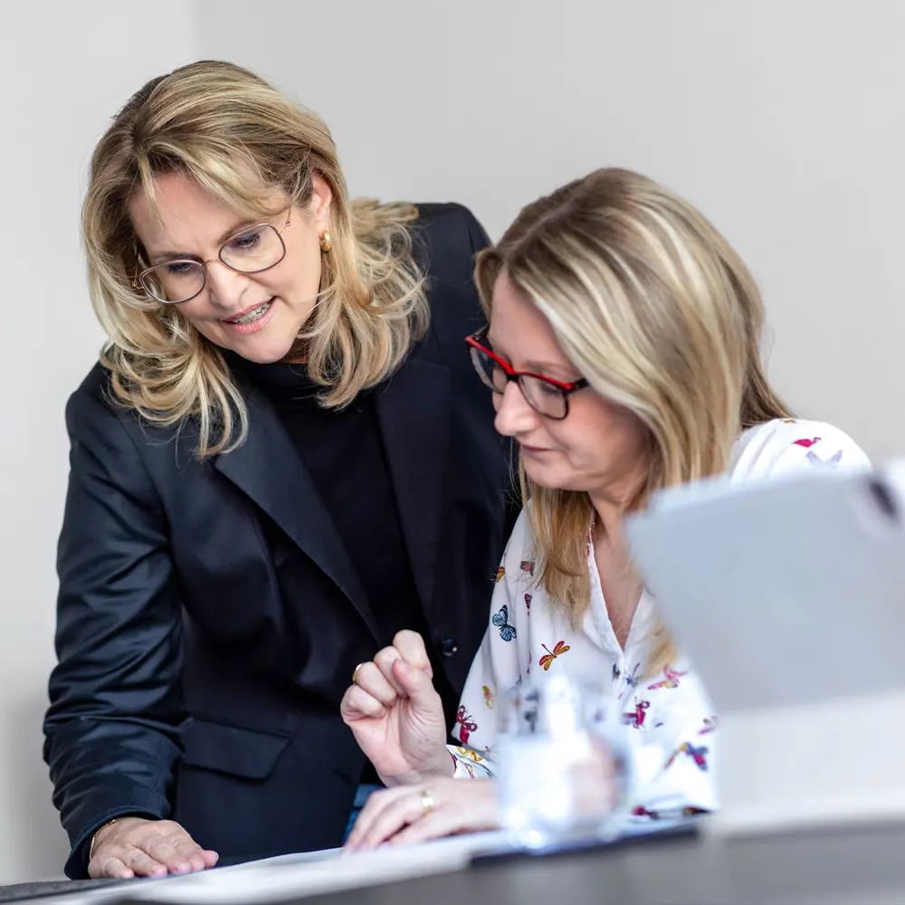 Nicole Flockenhaus beugt sich zu Britta Kadach von S73, erklärt ihr Unterlagen in einfacher, verständlicher Sprache