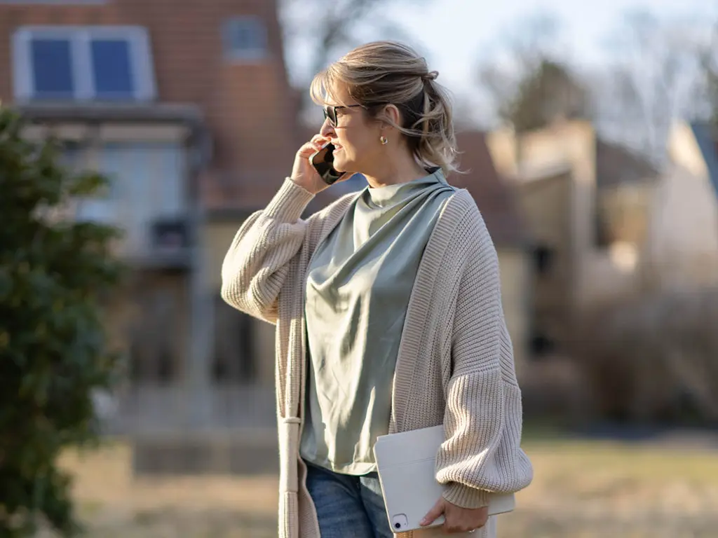 Nicole Flockenhaus telefoniert in der Natur, sie führt ein Gespräch im Rahmen ihres Coachings für Führungskräfte