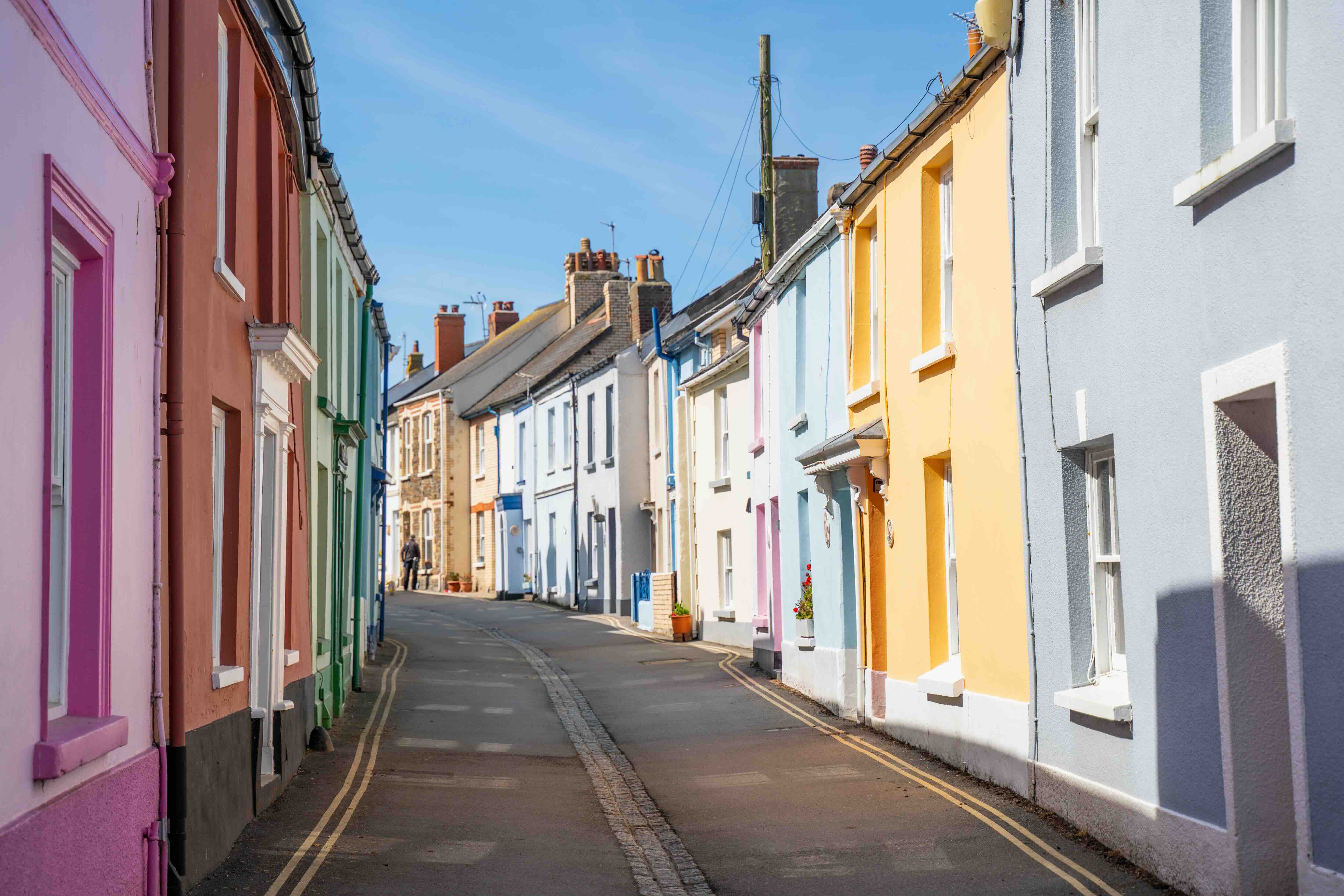 Narrow street lined with colourful pastel houses under a blue sky.