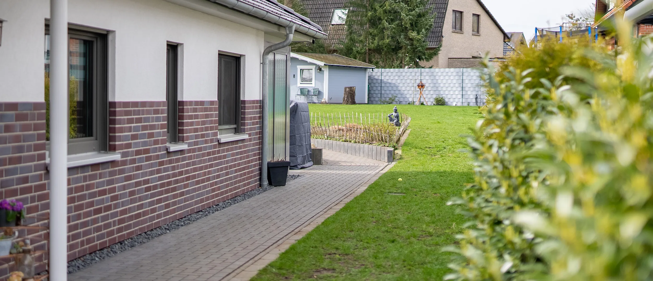 Barrierefreie Dusche mit Holzpaneelen, verchromtem Duschkopf und Sitzbank aus grauen Fliesen.