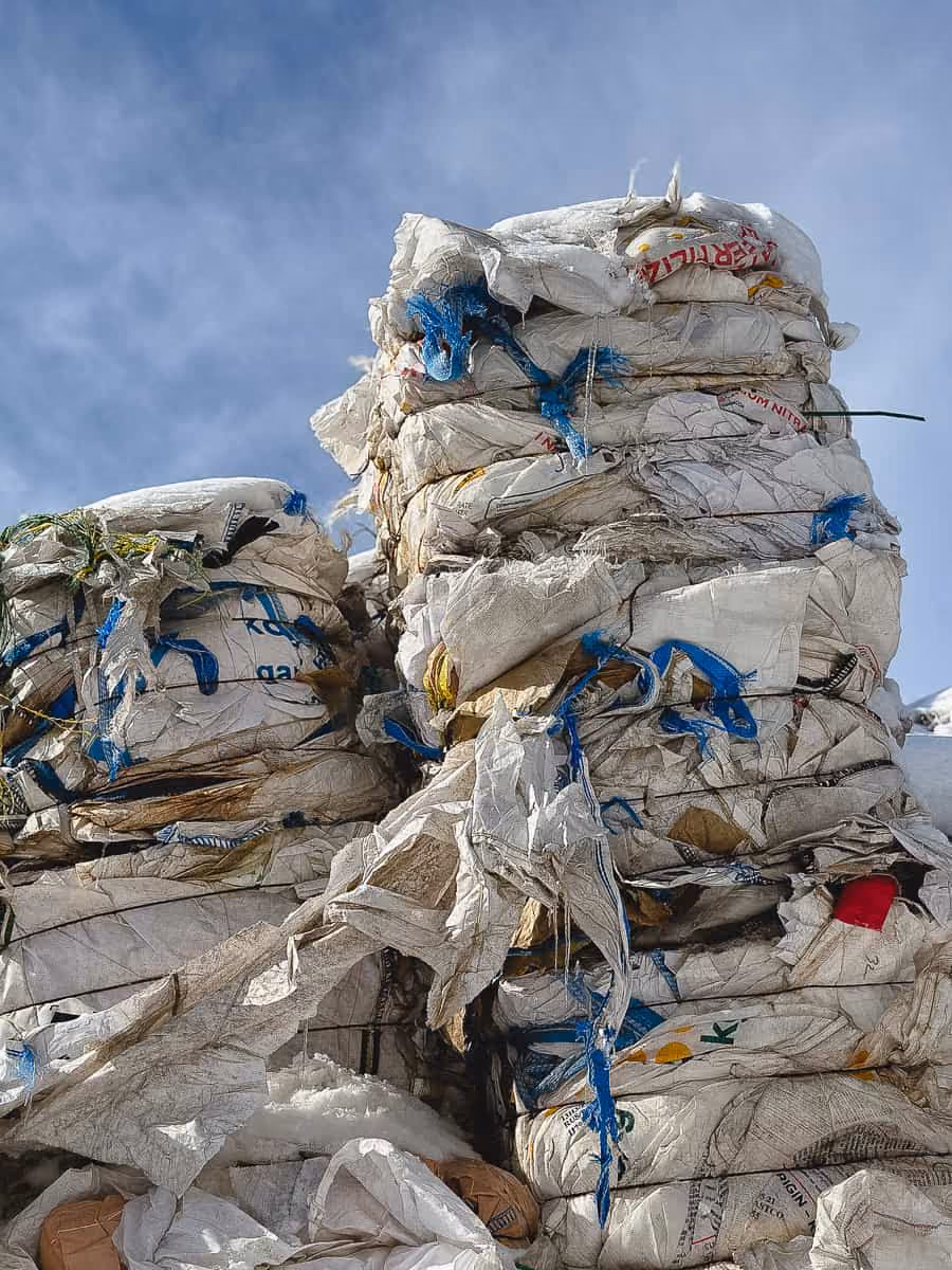 Large stacks of compressed white bags with blue and red markings against a blue sky.