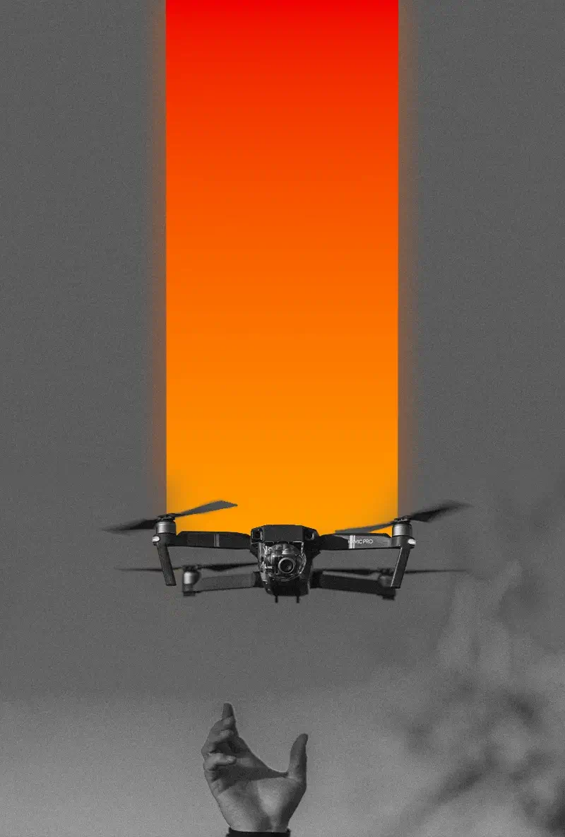 Black drone hovering above an outstretched hand with an orange-red vertical gradient in the background.