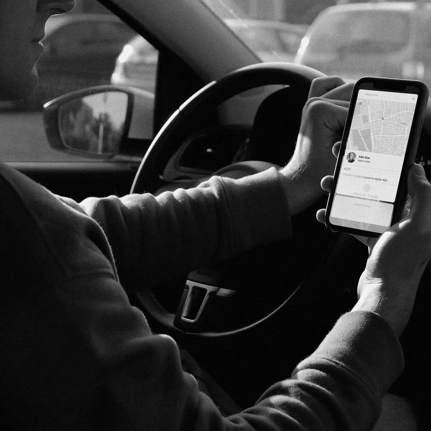 Person holding a smartphone displaying a map and alert message inside a car.