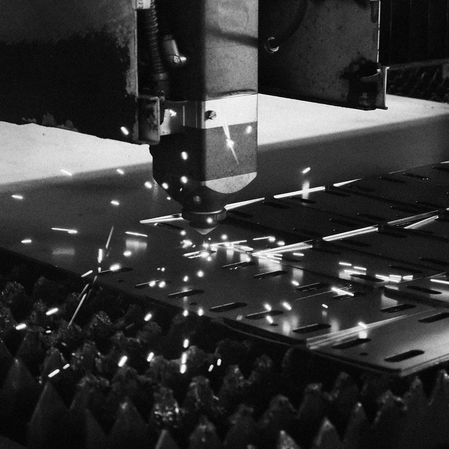 Close-up of a CNC laser cutting machine producing sparks while cutting metal sheets.