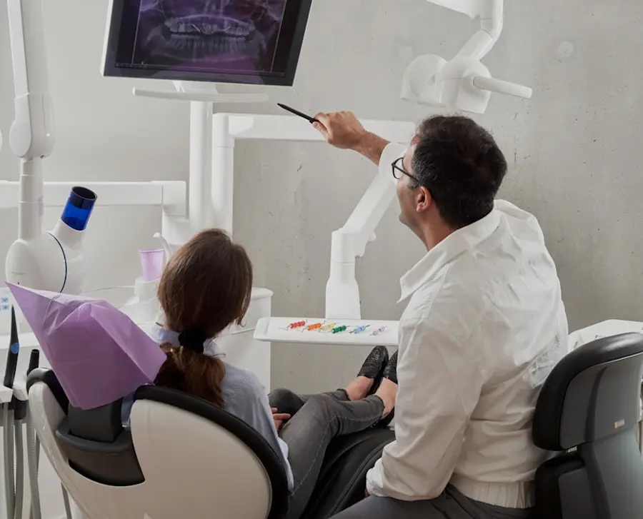 Dentist explaining a dental X-ray to a patient seated in a dental chair in a modern clinic.