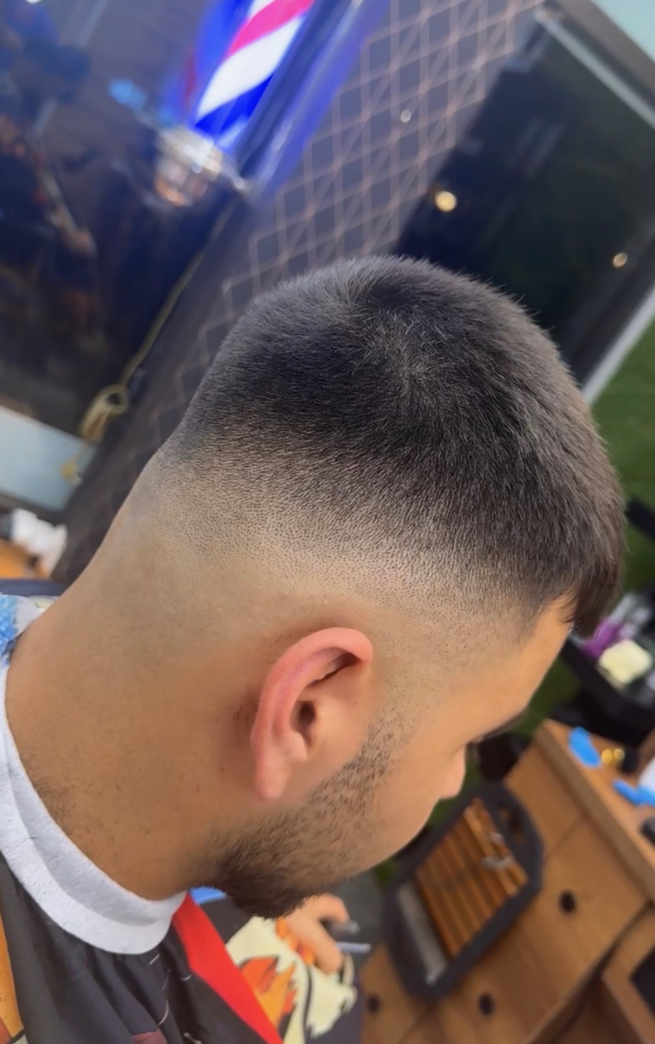 Side view of a man's head with a fresh short fade haircut in a barbershop.