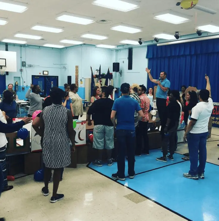 Adults gathered in school gymnasium during a group activity session
