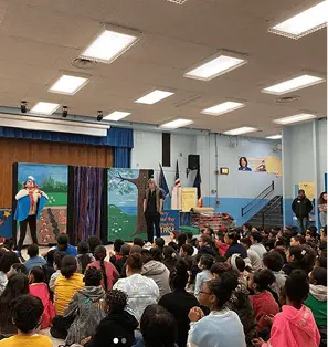 Students watching a live performance in school auditorium assembly