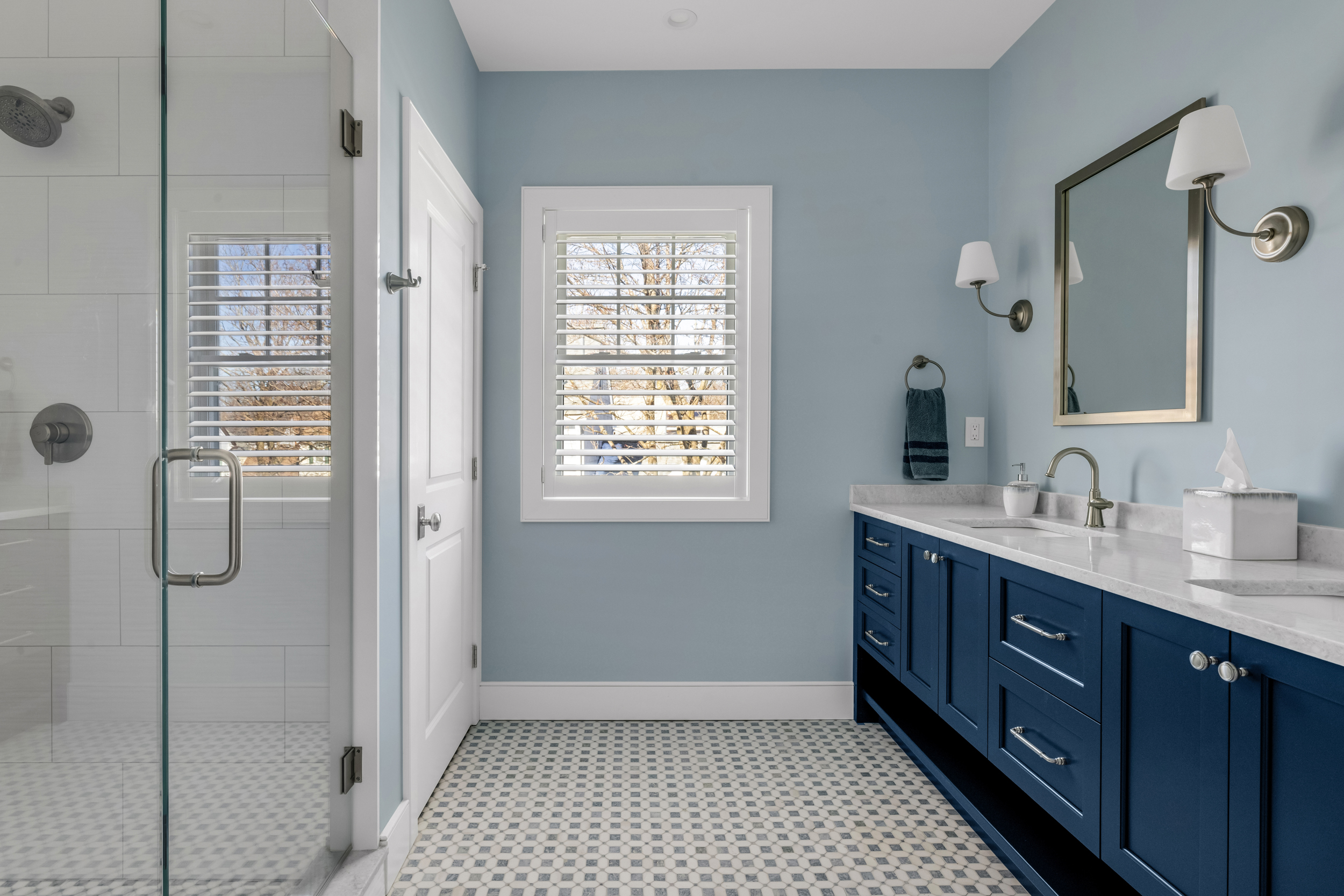 Primary bathroom with mosaic tile floor, glass shower, and navy blue double vanity in Milton MA
