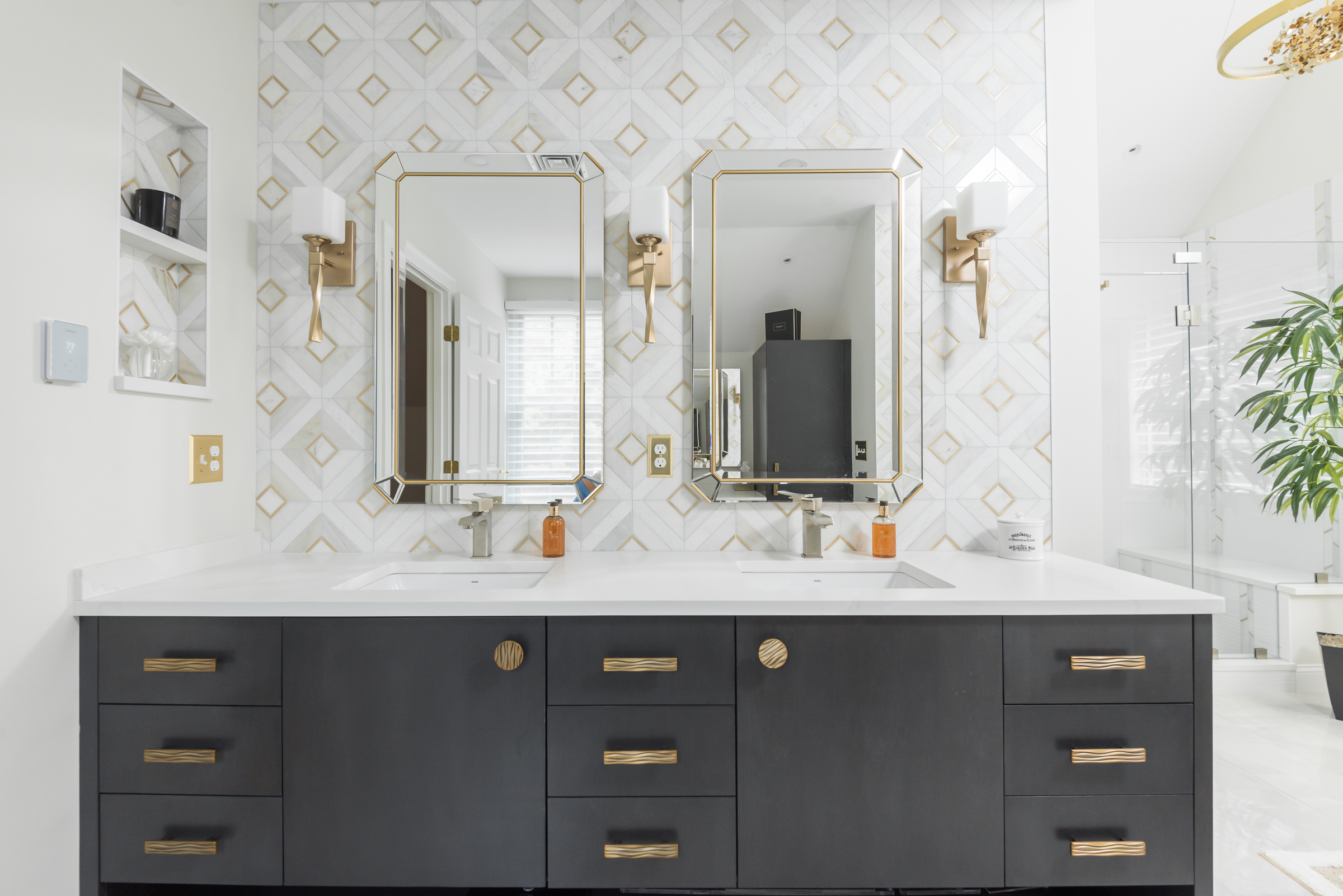 Glass-enclosed walk-in shower built for two with marble and brushed gold tile