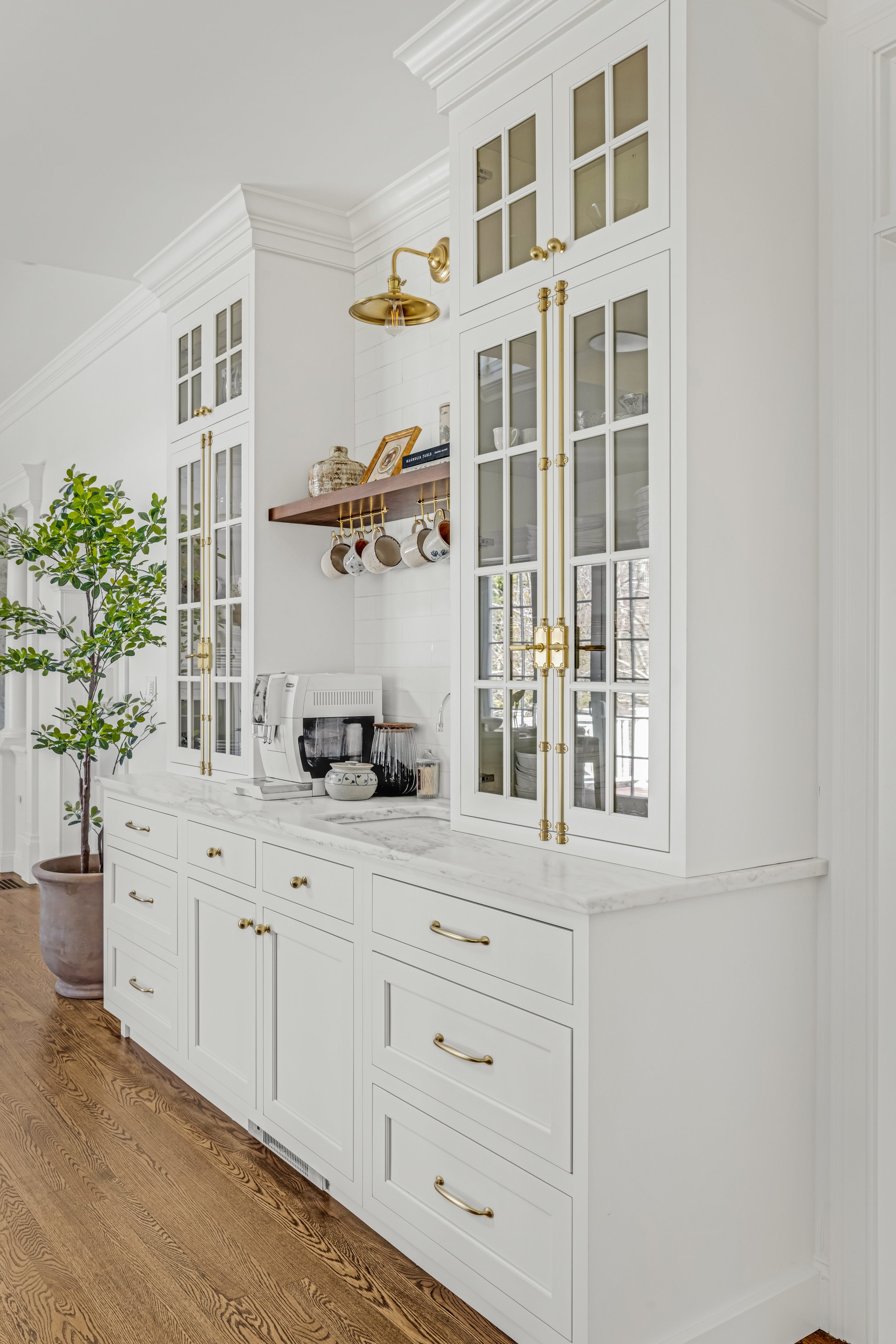 Detail of built-in hutch with glass-front cabinetry and statement lighting