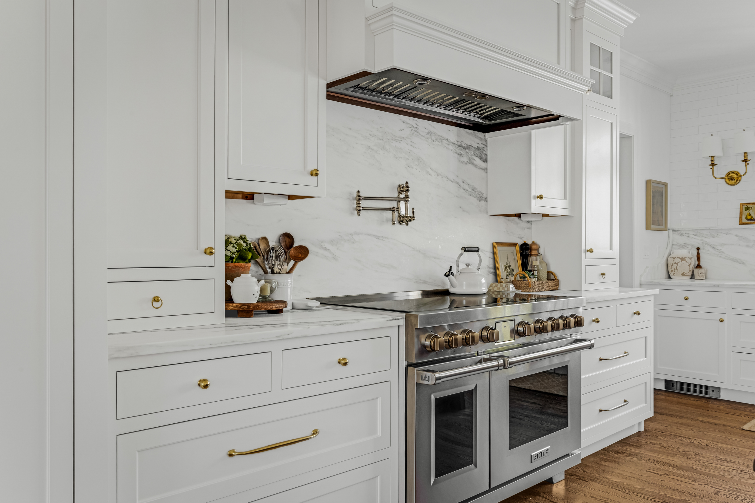 Glass-front upper cabinets with in-cabinet lighting in a white Norwell kitchen