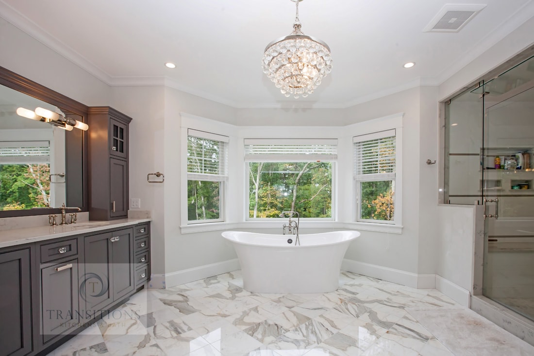 Transitional Norwell primary bathroom with a glass-door shower, freestanding tub, marble floor, and gray Centra vanity