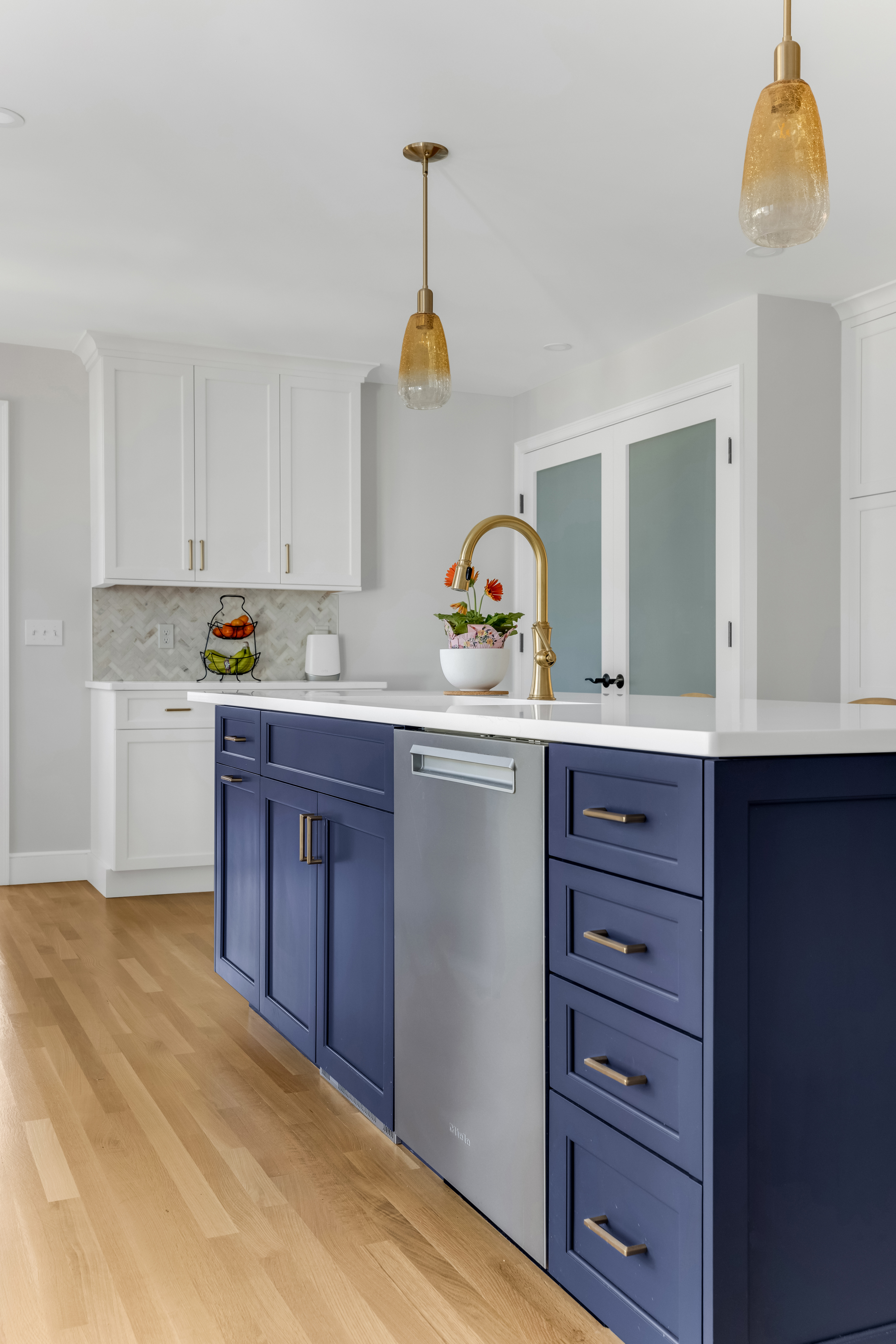 Close-up of navy blue shaker cabinets with brushed brass hardware and white quartz countertop