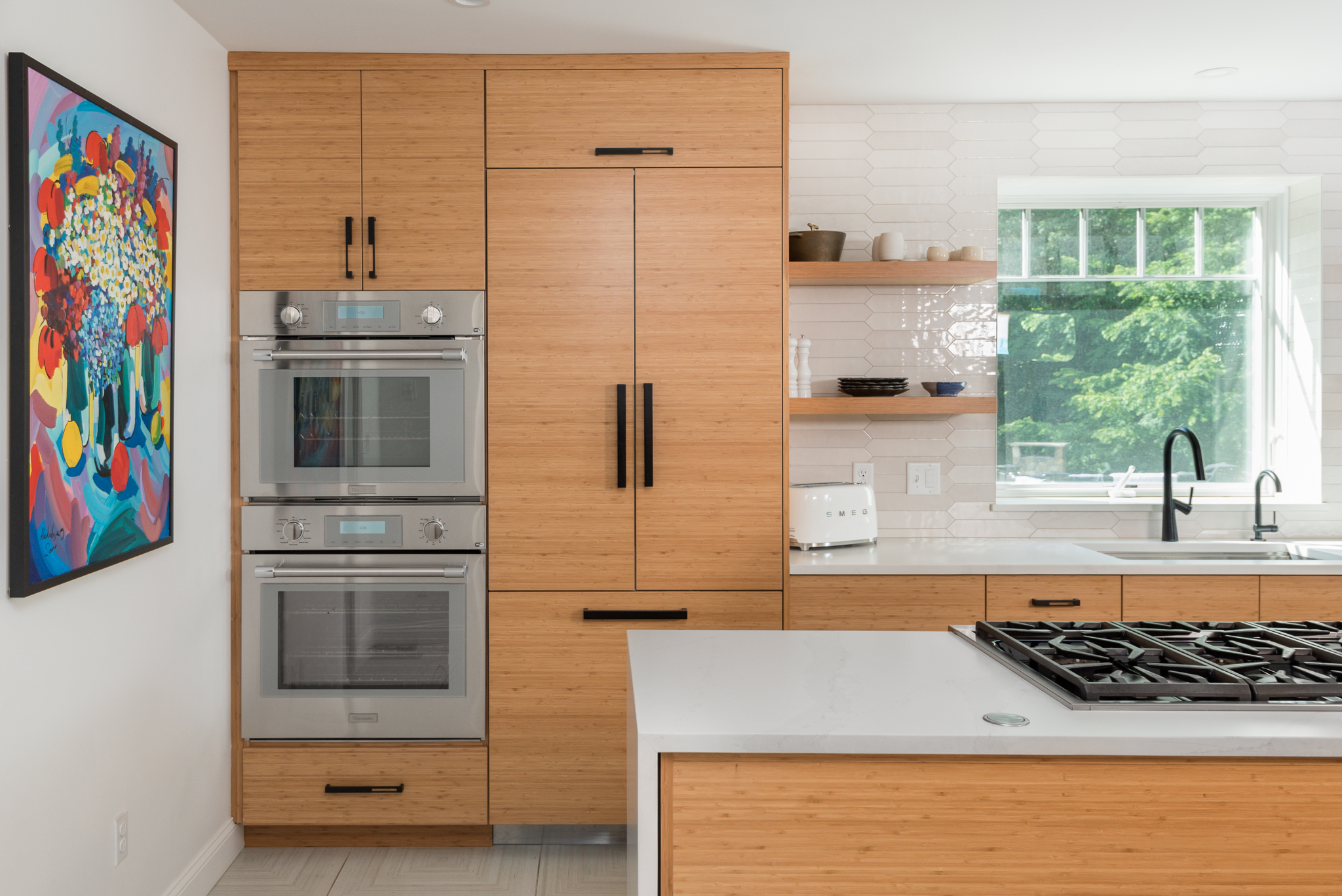 Modern frameless wood kitchen cabinets with paneled refrigerator and double oven in Hanover MA