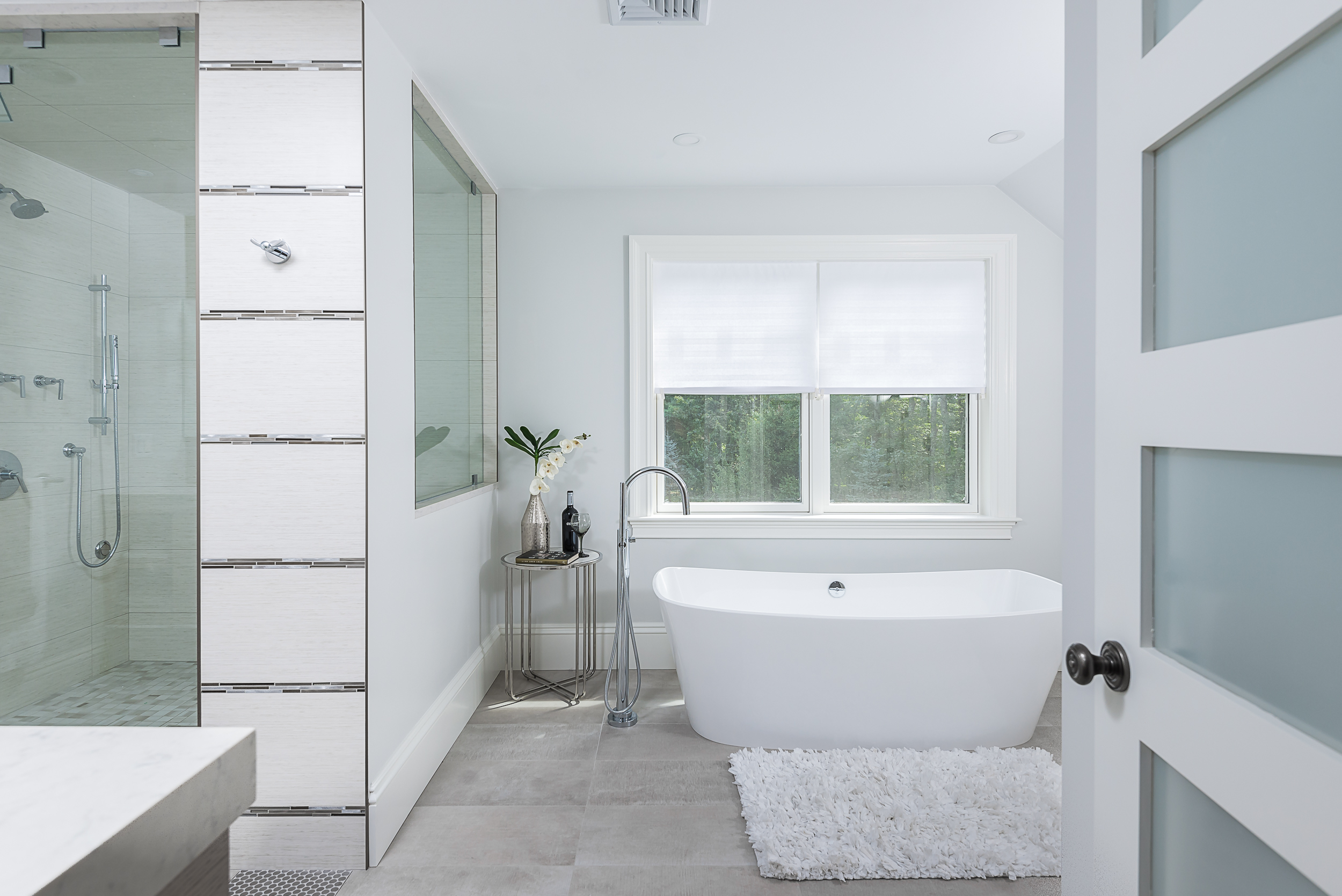 Spa-style bathroom with freestanding soaking tub and vertical mosaic tile feature wall