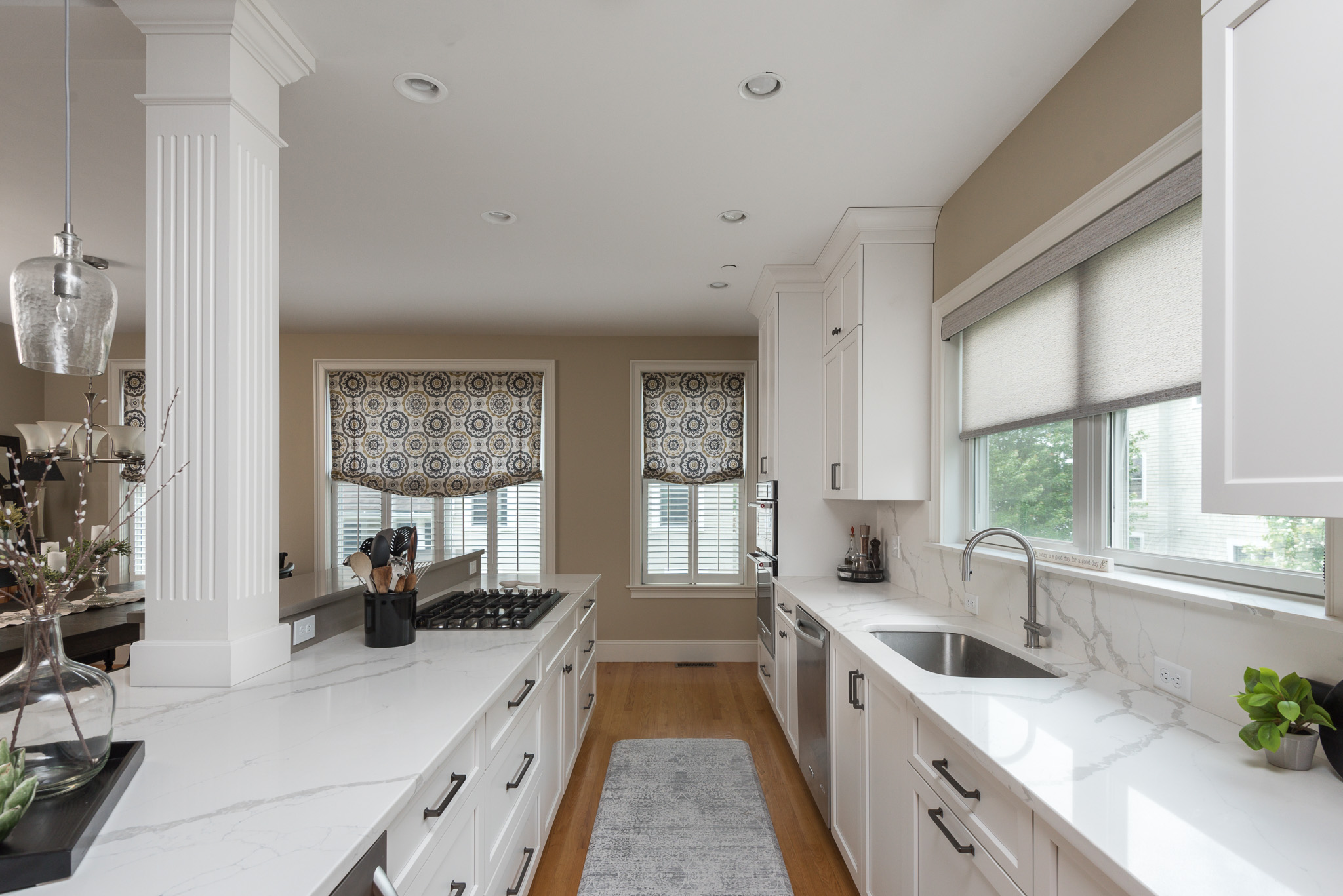 Long narrow kitchen with white cabinets, marble countertops, and fluted columns in Scituate MA