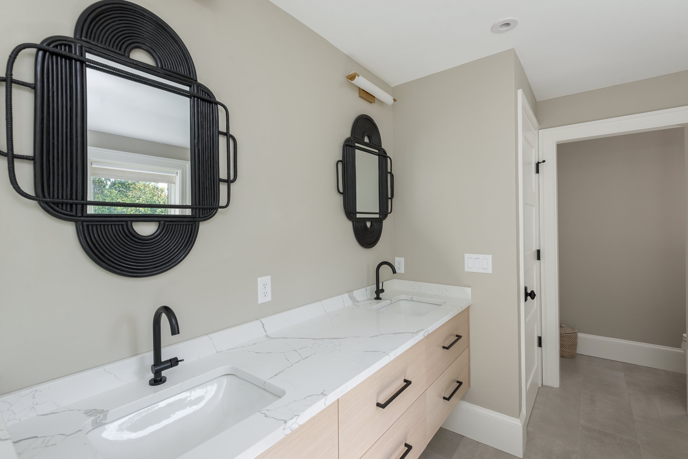 Undermount soaking tub on quartz deck with matte black tub filler beside corner walk-in shower in Hingham primary bath.