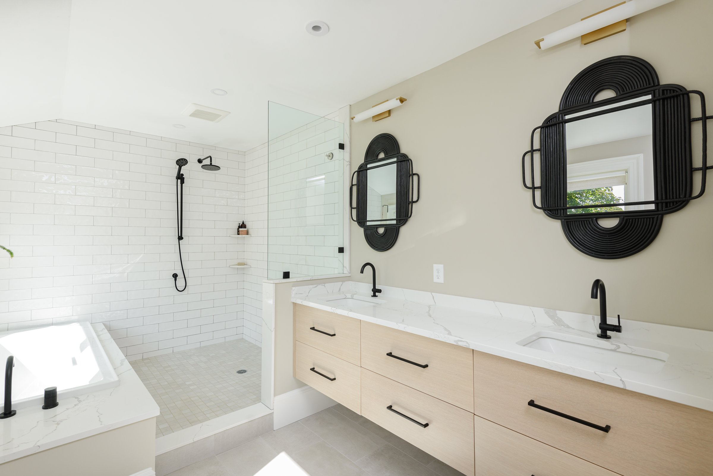Corner walk-in shower with stacked white subway tile, matte black rainhead, and tile niche in Hingham primary bath.
