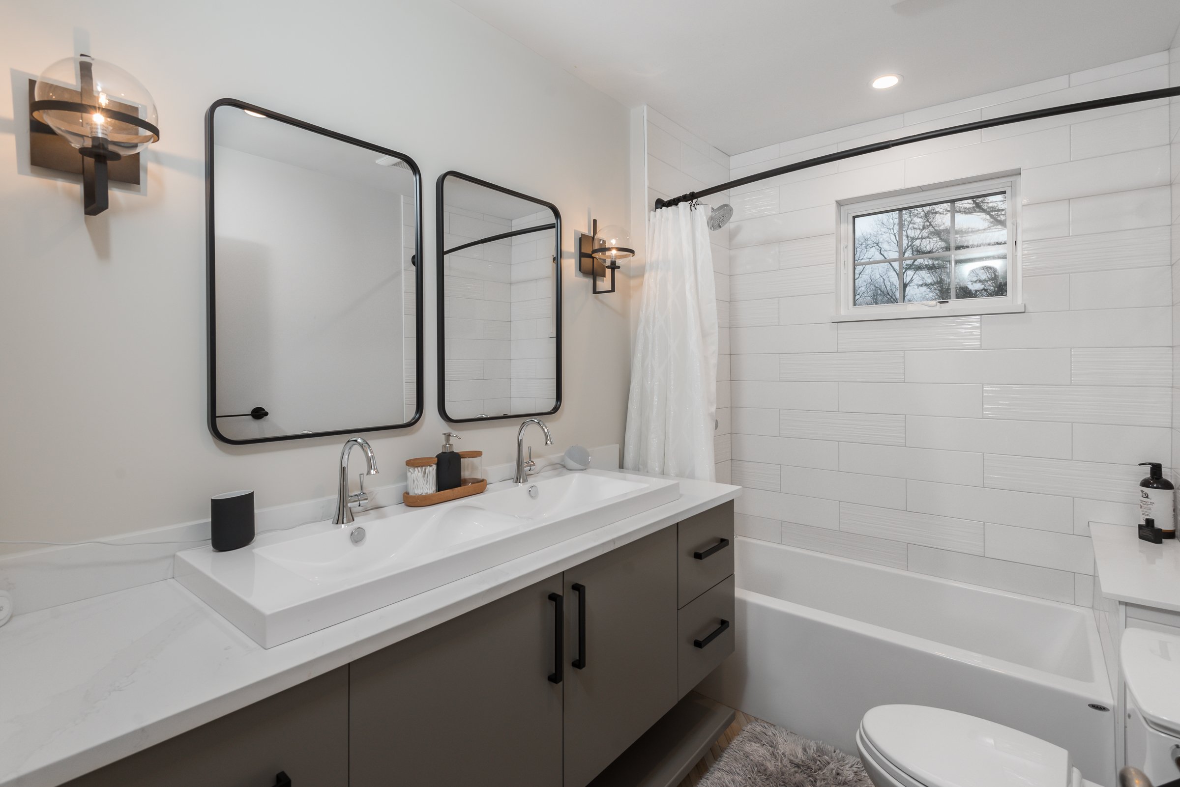 Family hall bath with Tedd Wood Ash Gray vanity, double trough sink, and Maaxx Rubix tub