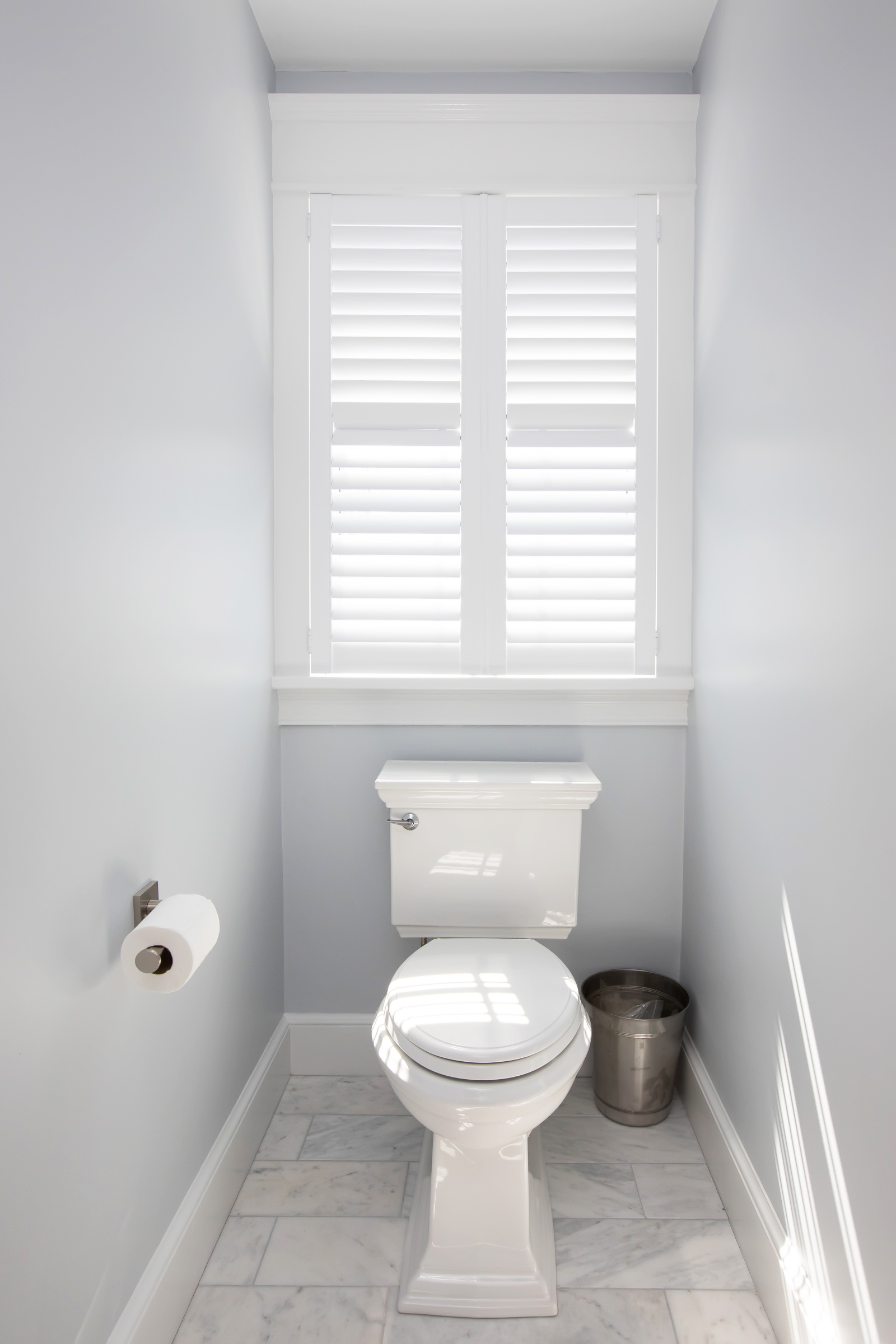 Separate water closet with marble floor and plantation shutters in the Hingham primary bath