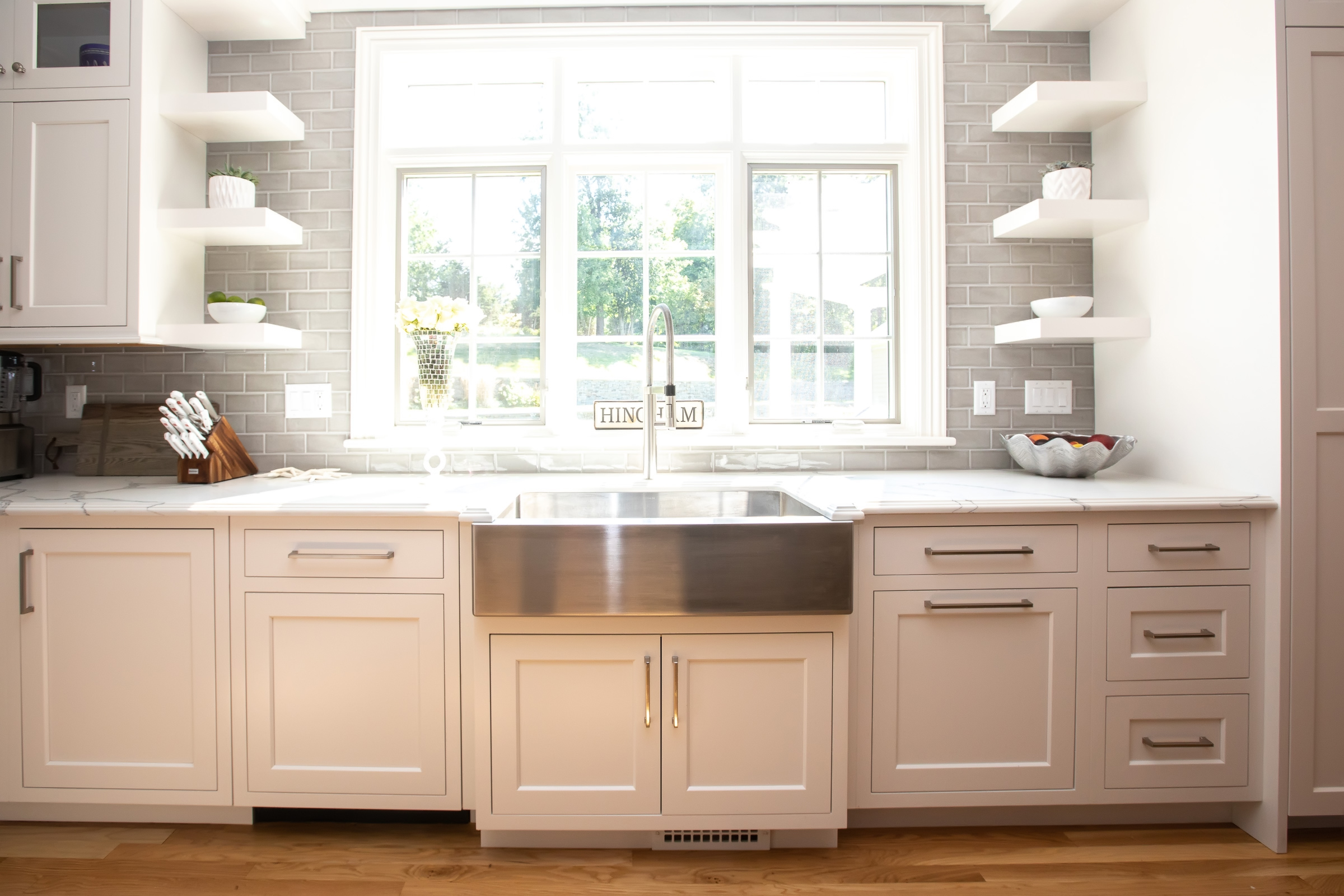 Cooking wall with stainless range, gray glass tile backsplash, and white Mouser cabinetry in Hingham