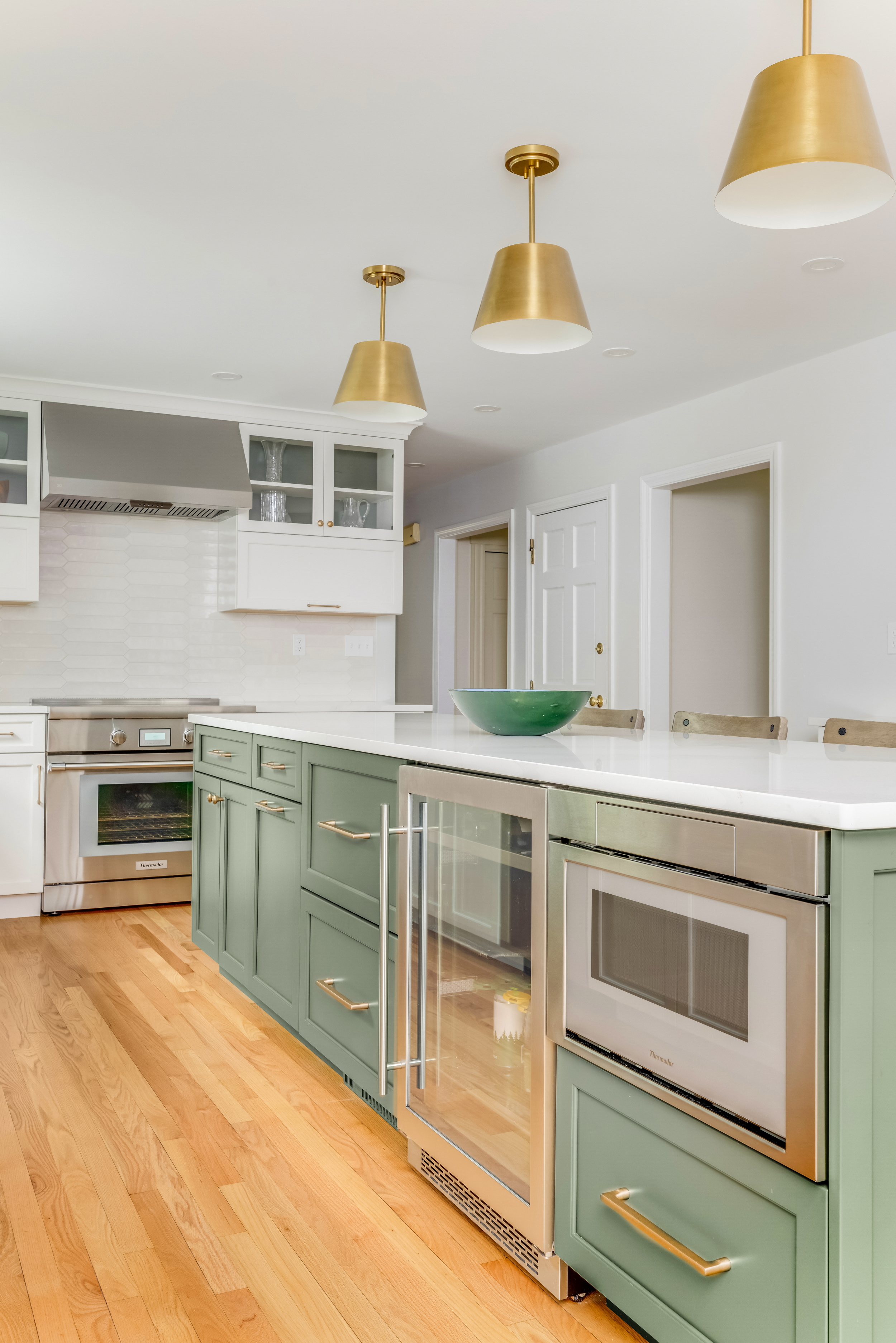 Kitchen island with beverage center, paneled microwave, and brass hardware