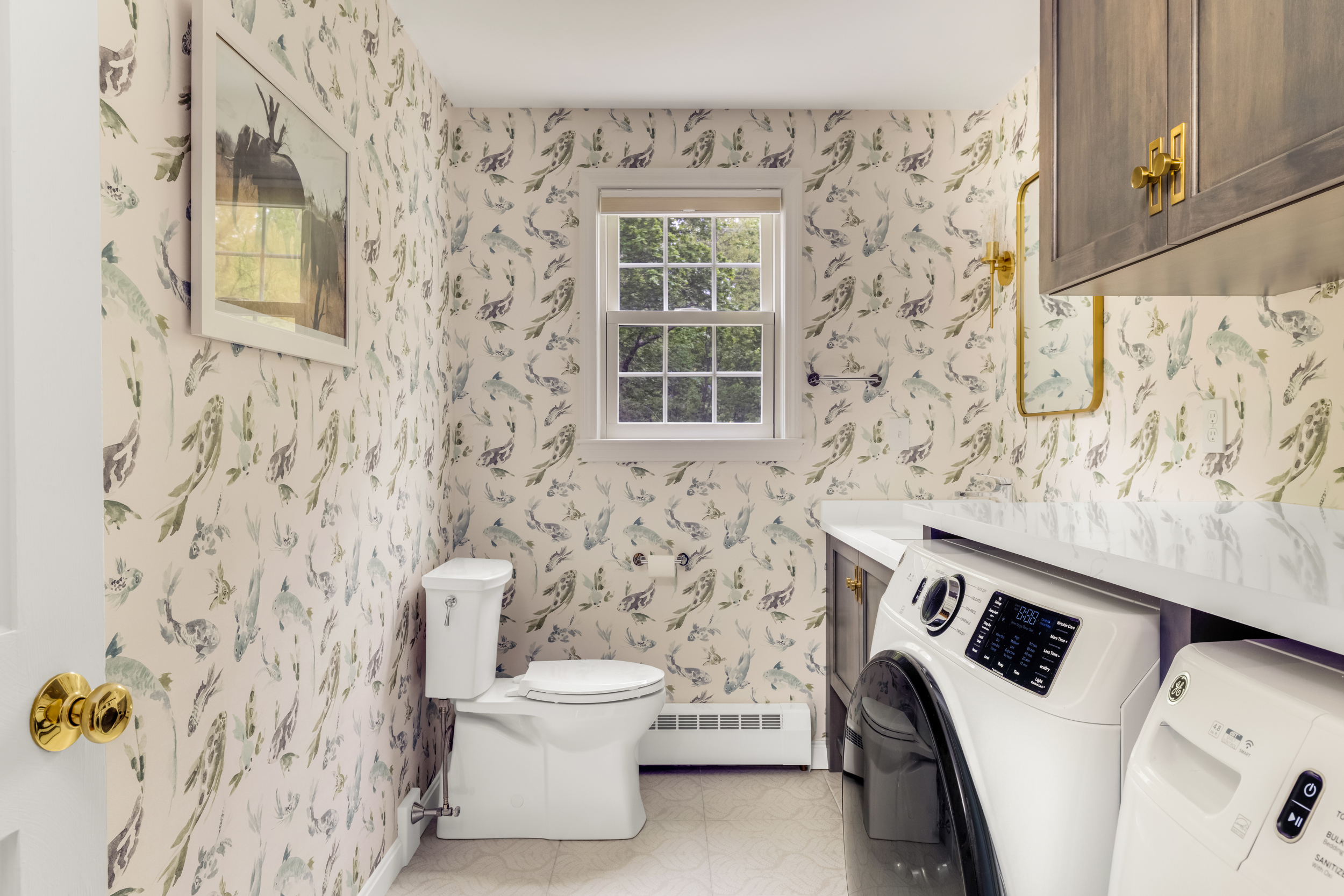 Half bath vanity with koi watercolor wallpaper, brass mirror, and quartz counter