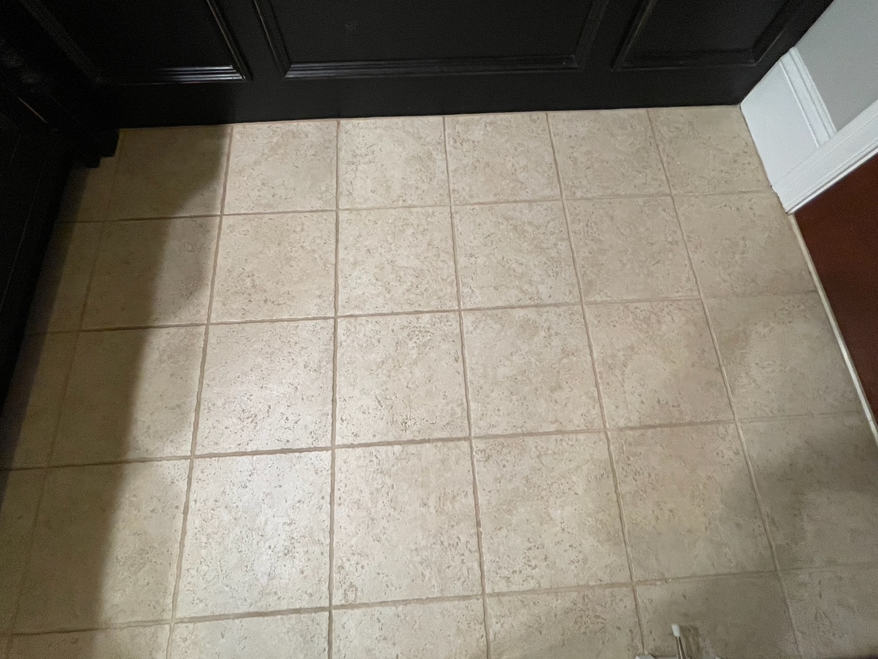 Before renovation: the original tan floor tile and dark vanity base in the Braintree primary bath.