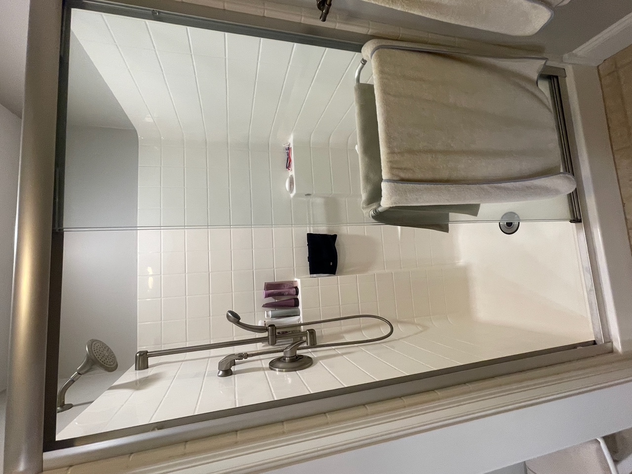Before renovation: the original enclosed fiberglass shower with a sliding glass door in the Braintree bath.