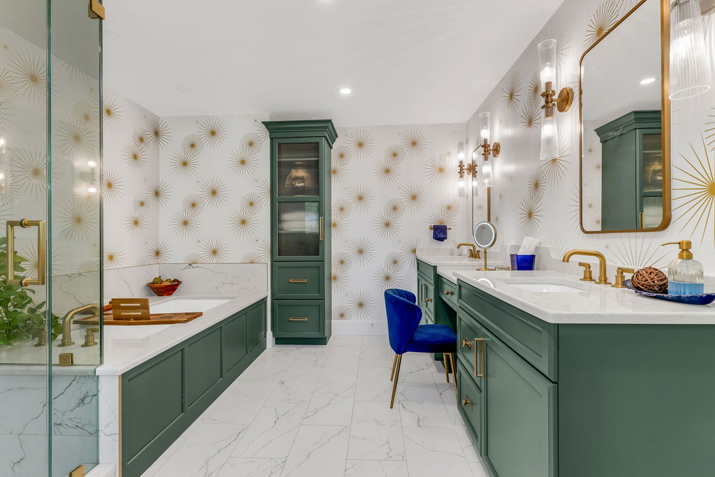 Emerald green double vanity and undermount tub in a Hingham primary bath with gold starburst wallpaper and brass fixtures