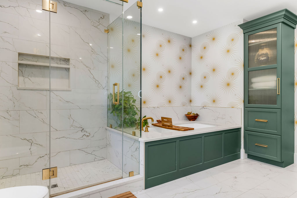 Frameless glass walk-in shower with marble-look tile beside a quartz tub deck in a Hingham primary bath