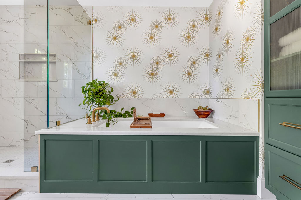 Undermount tub with a quartz deck and green wainscot panel against gold starburst wallpaper in Hingham