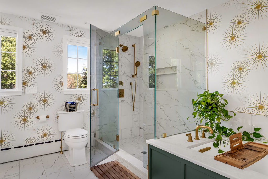 Walk-in glass shower, toilet, and green vanity with marble-look tile in a Hingham primary bath